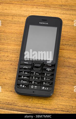Milan, Lombardy, Italy- April 30, 2025 : Classic Nokia 301 cellphone placed on a wooden surface, displaying a blank screen Stock Photo