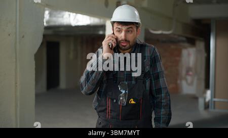 Caucasian man foreman builder talking mobile phone on construction site problem building stressed guy civil engineer architect repairman handyman feel Stock Photo