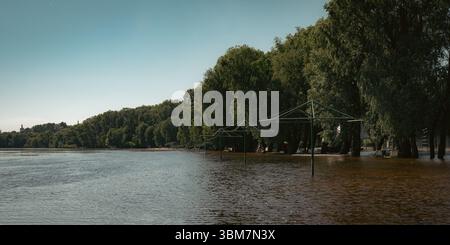 The image showcases the calm water meeting lush, green shores, highlighting the harmony between water and land. Stock Photo