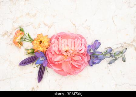 Colorful bouquet floral layout with pink, orange, and purple flowers arranged on a light marble surface, top view. Flat lay Stock Photo