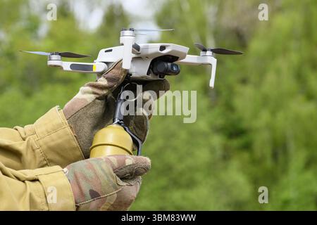 Operator in military colored clothes Preparing a drone for flight attached grenade outdoor Stock Photo