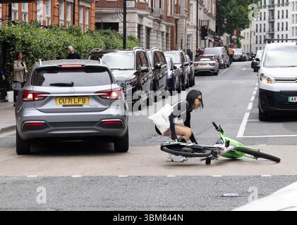 pic shows:  London scene  Young woman knocked off her Lime bike by an Uber driver outside Claridges Hotel in Mayfair yesterday. The car driver seemed Stock Photo