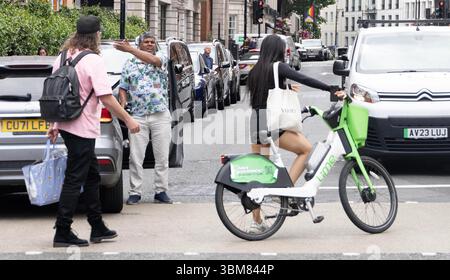 pic shows:  London scene  Young woman knocked off her Lime bike by an Uber driver outside Claridges Hotel in Mayfair yesterday. The car driver seemed Stock Photo