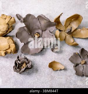Creating Clay Flower: DIY ceramic Workshop Idea. Different spring clay flowers from dark and yellow clays, pieces of raw clay. Light background. Top v Stock Photo