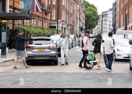 pic shows:  London scene  Young woman knocked off her Lime bike by an Uber driver outside Claridges Hotel in Mayfair yesterday. The car driver seemed Stock Photo