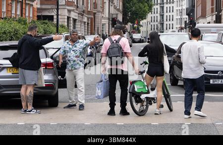 pic shows:  London scene  Young woman knocked off her Lime bike by an Uber driver outside Claridges Hotel in Mayfair yesterday. The car driver seemed Stock Photo