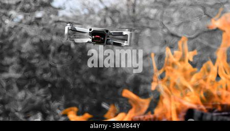 Flying drone Quadcopter with camera pointed at viewer outdoor in a fire in the foreground spurts of flame Stock Photo