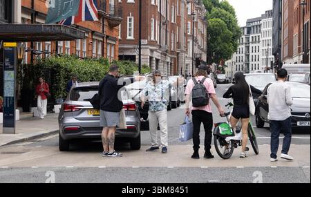 pic shows:  London scene  Young woman knocked off her Lime bike by an Uber driver outside Claridges Hotel in Mayfair yesterday. The car driver seemed Stock Photo