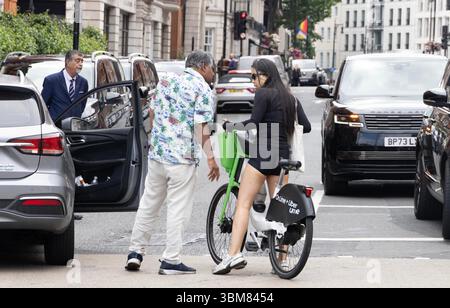 pic shows:  London scene  Young woman knocked off her Lime bike by an Uber driver outside Claridges Hotel in Mayfair yesterday. The car driver seemed Stock Photo
