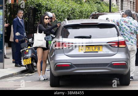 pic shows:  London scene  Young woman knocked off her Lime bike by an Uber driver outside Claridges Hotel in Mayfair yesterday. The car driver seemed Stock Photo