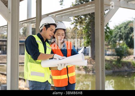 Construction Teamwork. Engineers analyzing plans together outdoors. Stock Photo