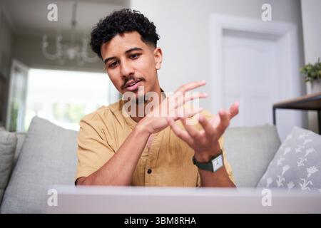 Young Professional Engaged in a Virtual Discussion from the Comfort of Home Stock Photo