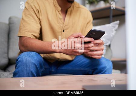 Man Relaxing at Home While Using Smartphone for Communication Stock Photo