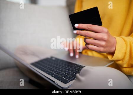 Close-Up of a Person Holding a Credit Card and Typing on a Laptop at Home Stock Photo
