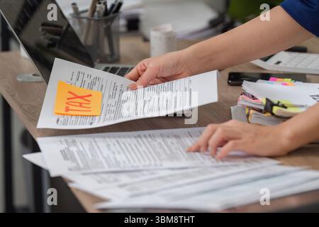 Tax Document Management. Individual organizing tax documents while preparing for filing and calculations. Stock Photo