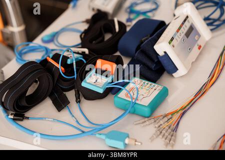 A close-up view shows a polysomnography PSG system including various electrodes, sensors, straps, and monitoring devices arranged on a white table for Stock Photo