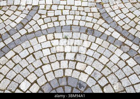 Close-up of traditional cobblestone pavement with radial fan pattern made of gray and dark gray stones. Ideal for architecture, urban planning, and te Stock Photo