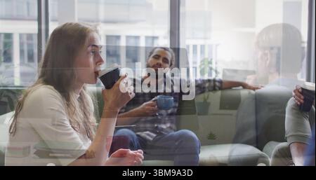 Drinking woman in sweater raising paper cup in office lounge, with sofa mugs windows, copy space. Collaboration, relaxation, coworking, modernity, cas Stock Photo
