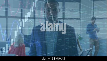 Standing senior executive in navy suit analyzing trends at office, with overlaid financial graphs. Business, finance, analytics, corporate, profession Stock Photo