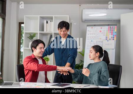 Creative Team Dynamics and Engagement. A group of young designers collaborating on ideas in a modern office environment. Stock Photo