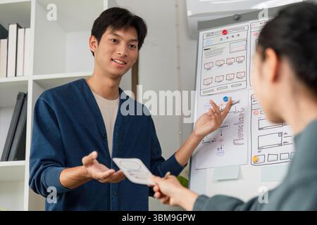 Team Collaboration and UX Design Presentation. A designer presenting a concept to colleagues while fostering creative discussions. Stock Photo