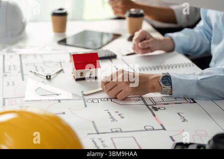 Architectural Planning and Collaboration. Professionals discussing building designs around a project layout. Stock Photo