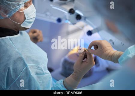 Middle Aged Male Surgeon Performing Operation in Modern Operating Room Stock Photo