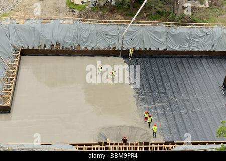 Concrete pouring over insulation sheets at construction site, modern building techniques and energy-efficient foundation work Stock Photo