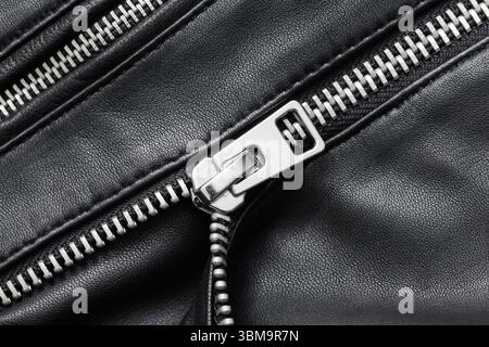 Closeup of black metal zipper on leather. Fashion detail of clothing accessory. Industrial sewing background. Garment manufacturing texture. Stock Photo