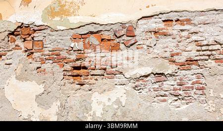 Weathered brick wall texture showing crumbling plaster and exposed red bricks, creating a rustic and aged backdrop Stock Photo