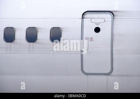 Close-up of a Boeing 737 MAX emergency exit door and passenger windows on the aircraft fuselage. Stock Photo