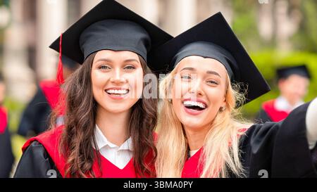 Happy young ladies in graduation clothes taking selfie Stock Photo