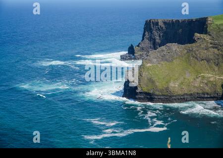 Sea stack and sea stump. View of sea stack and sea stump near cliffs with waves crashing in the ocean off the coast of Ireland. Stock Photo