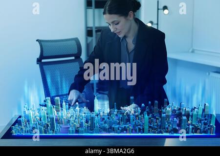 Building information modelling. Woman using holographic projection of city in office Stock Photo