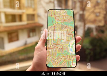 Woman looking at city map on her mobile phone outdoors, closeup Stock Photo