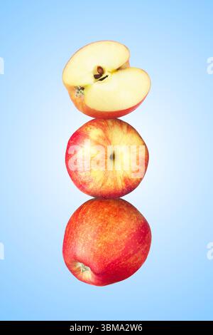 Apples stacked on top of each other against light blue background. Balance Stock Photo