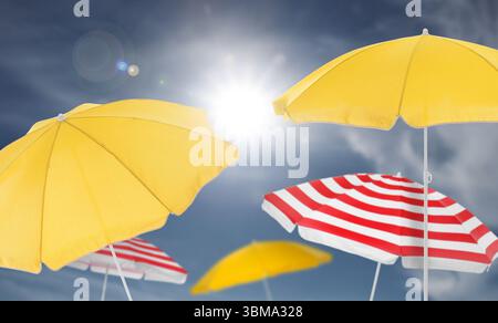 Different bright beach umbrellas against blue sky on sunny day Stock Photo
