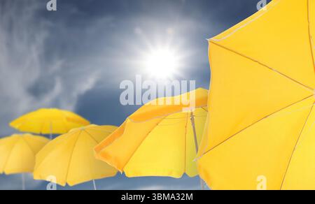 Yellow beach umbrellas against blue sky on sunny day Stock Photo