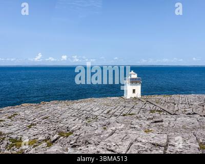 Black Head Lighthouse. Small white navigation beacon on the limestone pavement coast of County Clare, Ireland, under a clear blue sky by the atlantic Stock Photo