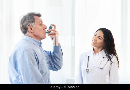 Physician examining mature man using blue asthma inhaler Stock Photo