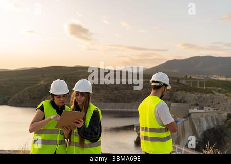Engineers using digital tablet and laptop at dam construction site Stock Photo