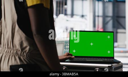 Black man adjusting robotic machinery settings through chroma key screen in solar panel manufacturing plant, diagnosing gear performance issues. Photovoltaics factory expert. Camera A. Stock Photo