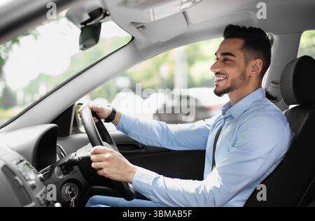 Joyful arabic guy driving nice auto, side view Stock Photo