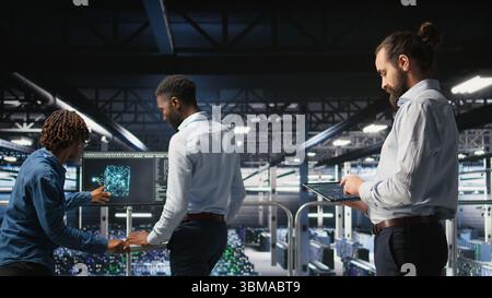 Programmers on data center industrial platform checking code on tablet, doing software updates. Server farm IT professionals cooperating, finetuning rackmounts configurations, Stock Photo