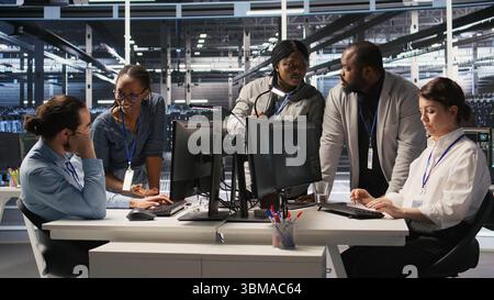 Engineering team in data center using AI automation during maintenance session. Server hub coworkers doing brainstorming, configuring deep learning models in hardware rigs, camera A Stock Photo
