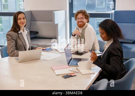 A Team Meeting is taking place in a Modern Office Setting that features Diverse Professionals Stock Photo