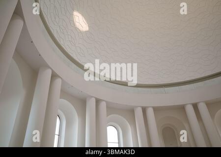 Interior of a modern rotunda, featuring a grand, white domed ceiling with an intricate geometric relief pattern. Stock Photo