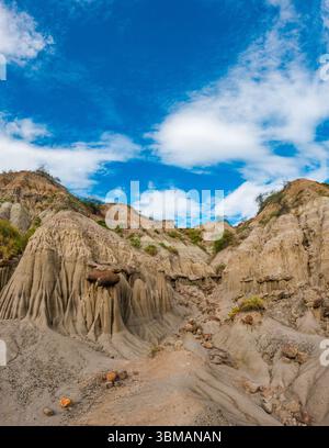Desert rock formations under bright blue sky with wind blown clouds ...