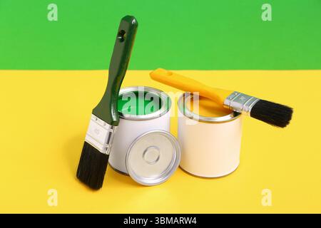 Cans of different paint and brushes on colorful background Stock Photo