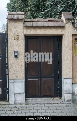 Gate No. 13 made of dark wood or metal, with rectangular panels, and is flanked by masonry pillars with a tiled roof, Bistrita, Romania 2025c Stock Photo